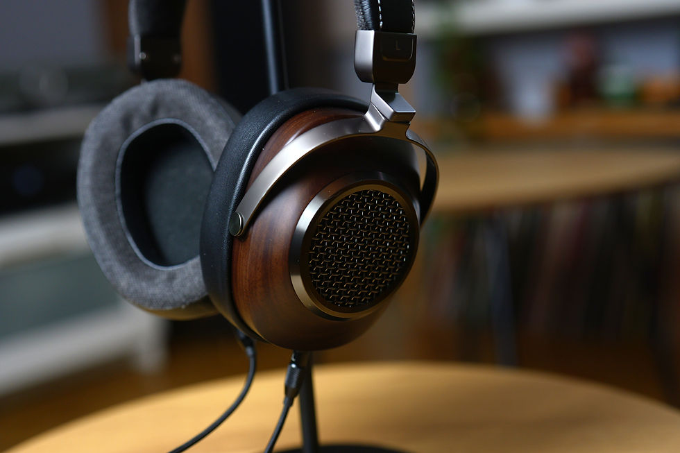 Close-up of stylish wooden headphones with gray cushions on a stand in a cozy room. Warm lighting, blurred background.