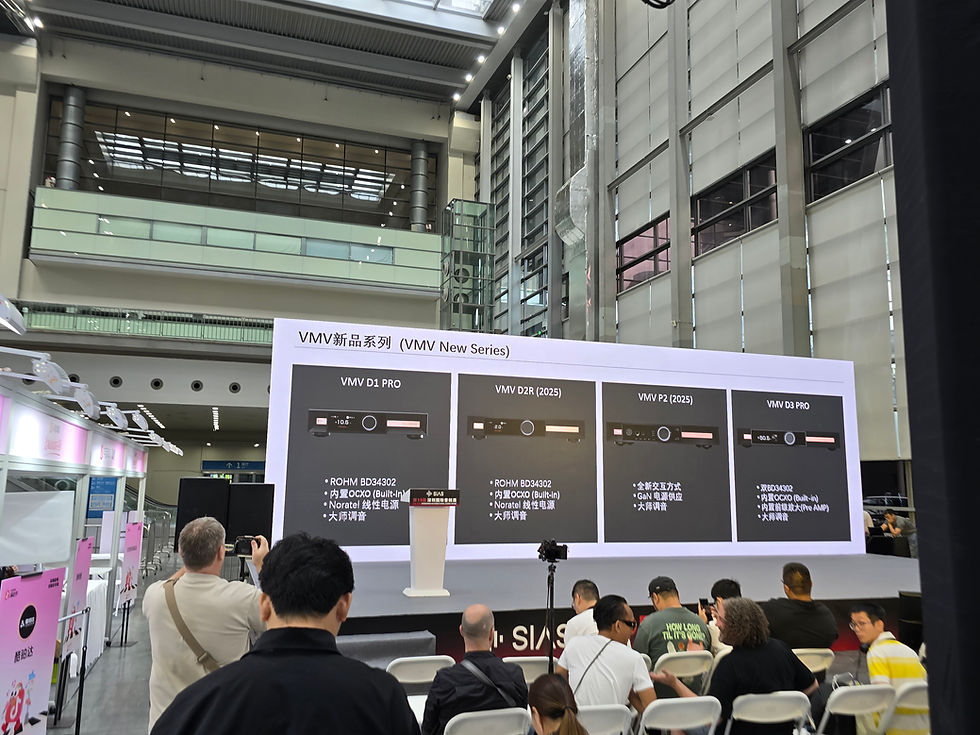 People seated in a modern hall watching a presentation on a large screen showcasing the "VMV New Series" audio products, with detailed specs.