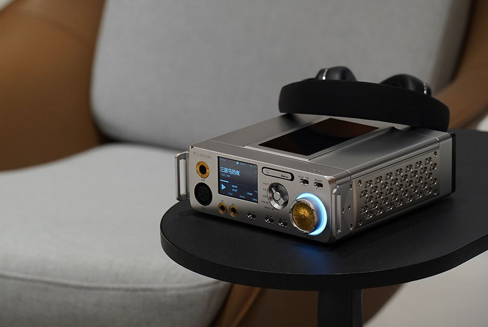 Silver audio device with headphones rests on a black table. Blue light glows around knob. Brown and gray chair in the blurred background.
