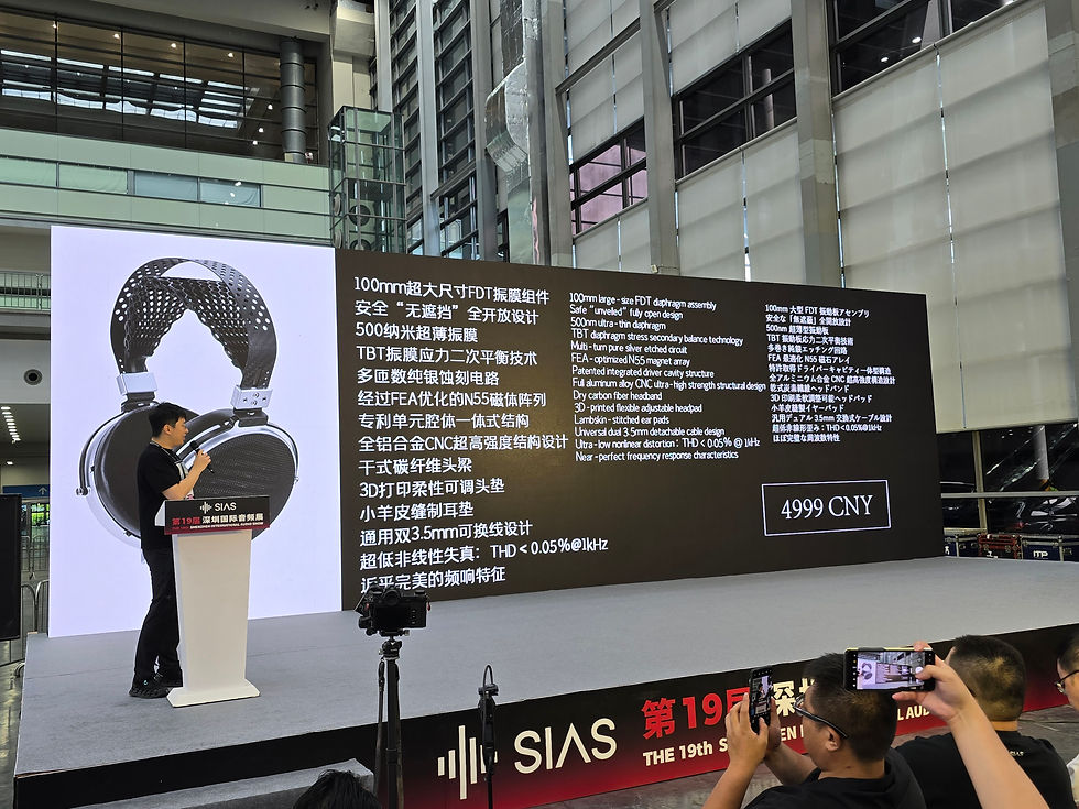 Man presents on stage with large screen displaying headphones and Chinese text. Price shown as 4999 CNY. Audience takes photos.