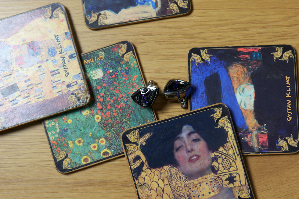 Decorative music coasters and two earbuds on a wooden table, with cards reading GYVTAN KLIMT.