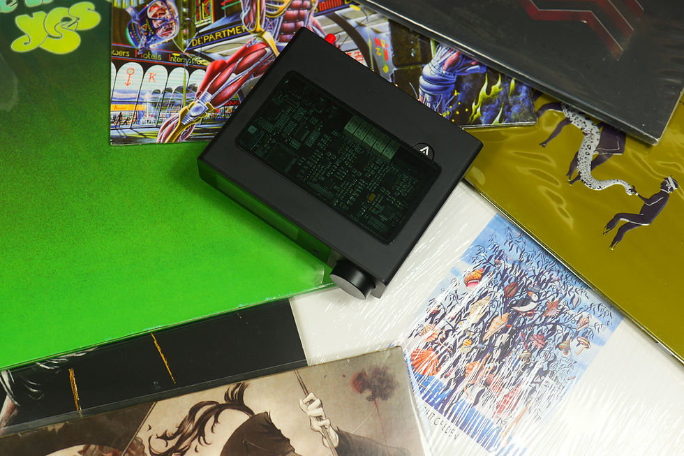 Black electronic device on colorful vintage album covers. Bright green, yellow, and intricate designs create a retro, artistic vibe.