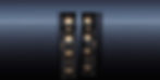 Two glossy black floorstanding speakers stand on a reflective blue floor against a gradient background.