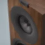 Close-up of a wooden speaker with visible KEF logo. It features a Uni-Q driver array and minimalist absorption technology text.