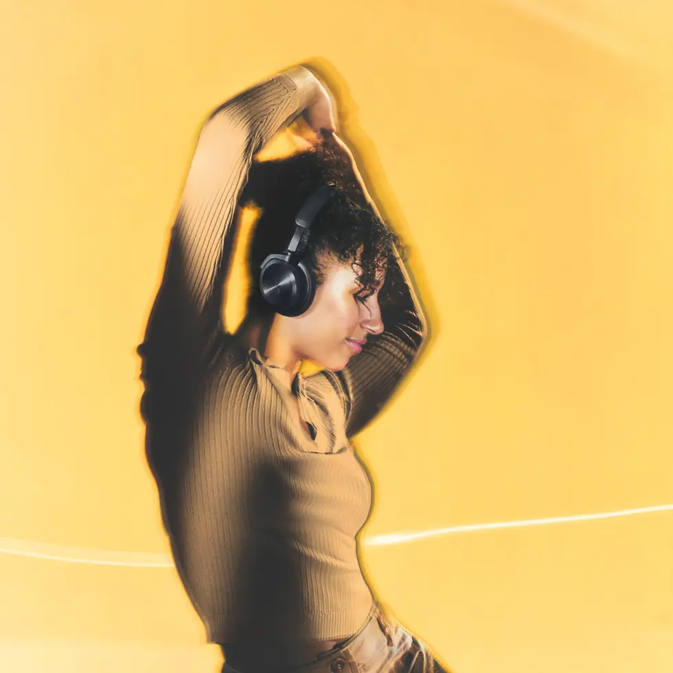 Person wearing headphones dances joyfully against a bright yellow background. They are in a brown top, showing a carefree mood.