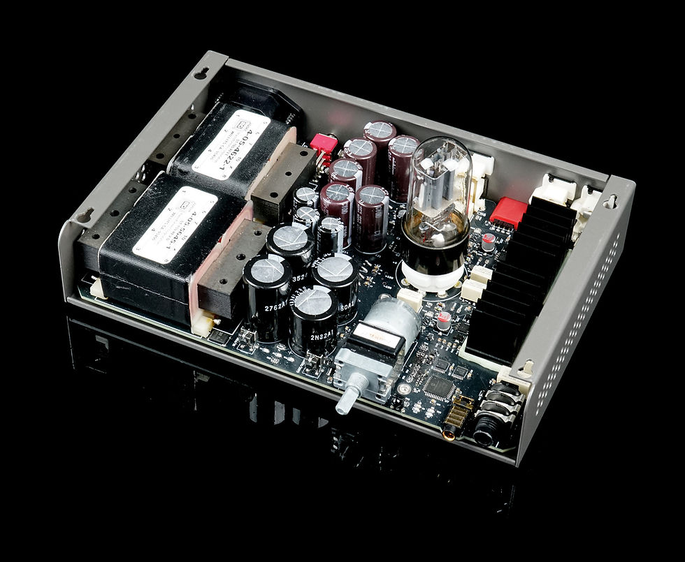 Audio amplifier circuit board with capacitors, a vacuum tube, and transformers, set on a reflective black surface.