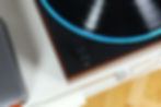 Close-up of a vinyl record on a turntable with blue LED ring, speed knob labeled 33, 45, and SPEED on a wood base