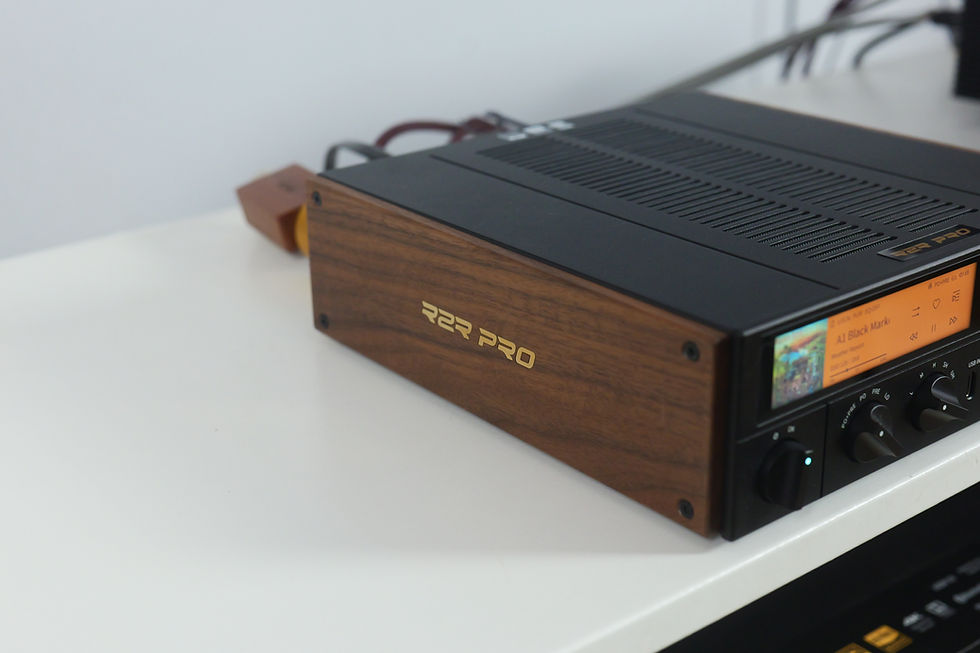 Wood-sided R2R PRO audio amplifier on a white shelf, with orange display and control knobs.