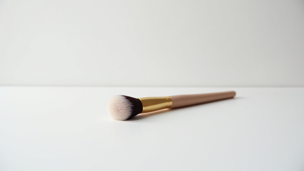 Eye-level view of a small, clean makeup brush resting on a white surface