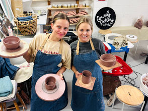 Two girls posing with their handmade pottery while taking a class at quirky pottery taupo