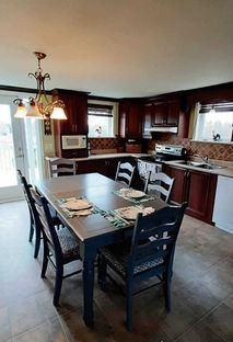 Salle à manger avec table et chaises dans la cuisine complète de la Maison Renée, location de chalet près de Québec.