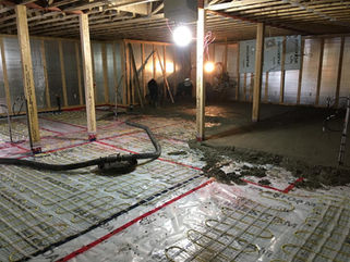 Pompe à ligne en action dans un sous-sol résidentiel pour le pompage de béton et le coffrage d’une dalle de béton résidentielle.