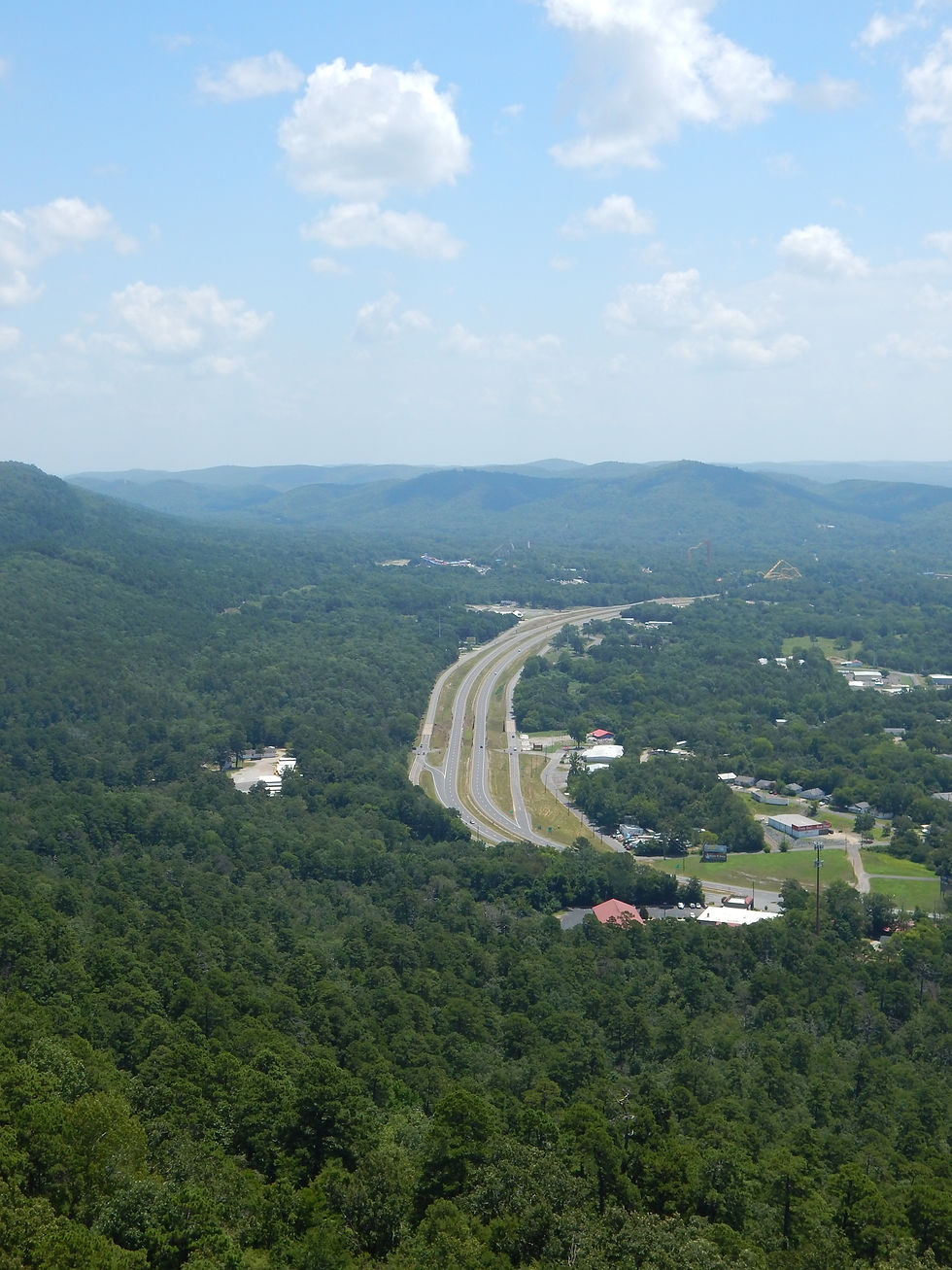 A highway surrounded by trees under a cloudy blue sky