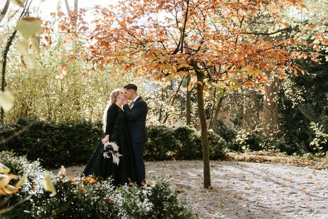 Brautpaar küsst sich zwischen Bäumen