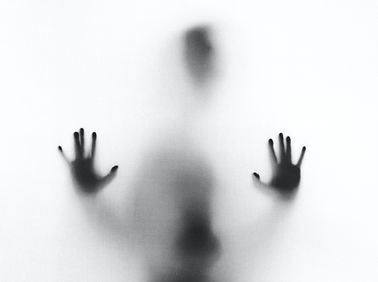 Silhoutte of hands and face behind a white translucent screen