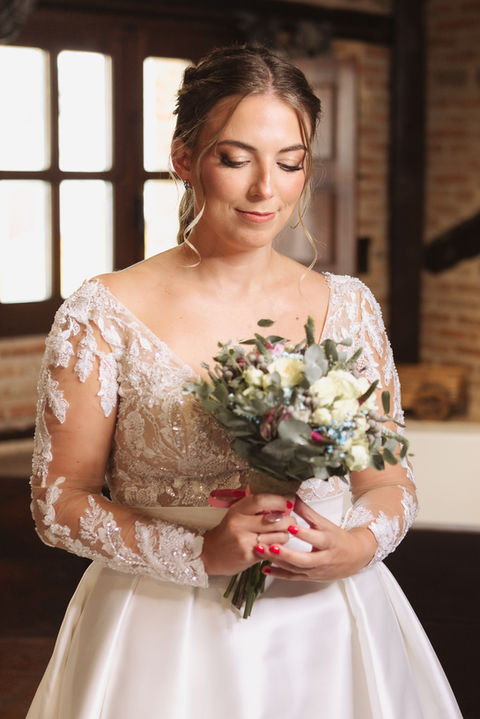 Emoción de la novia mirando su ramo durante los preparativos de su boda en Madrid, en Finca La Caprichosa
