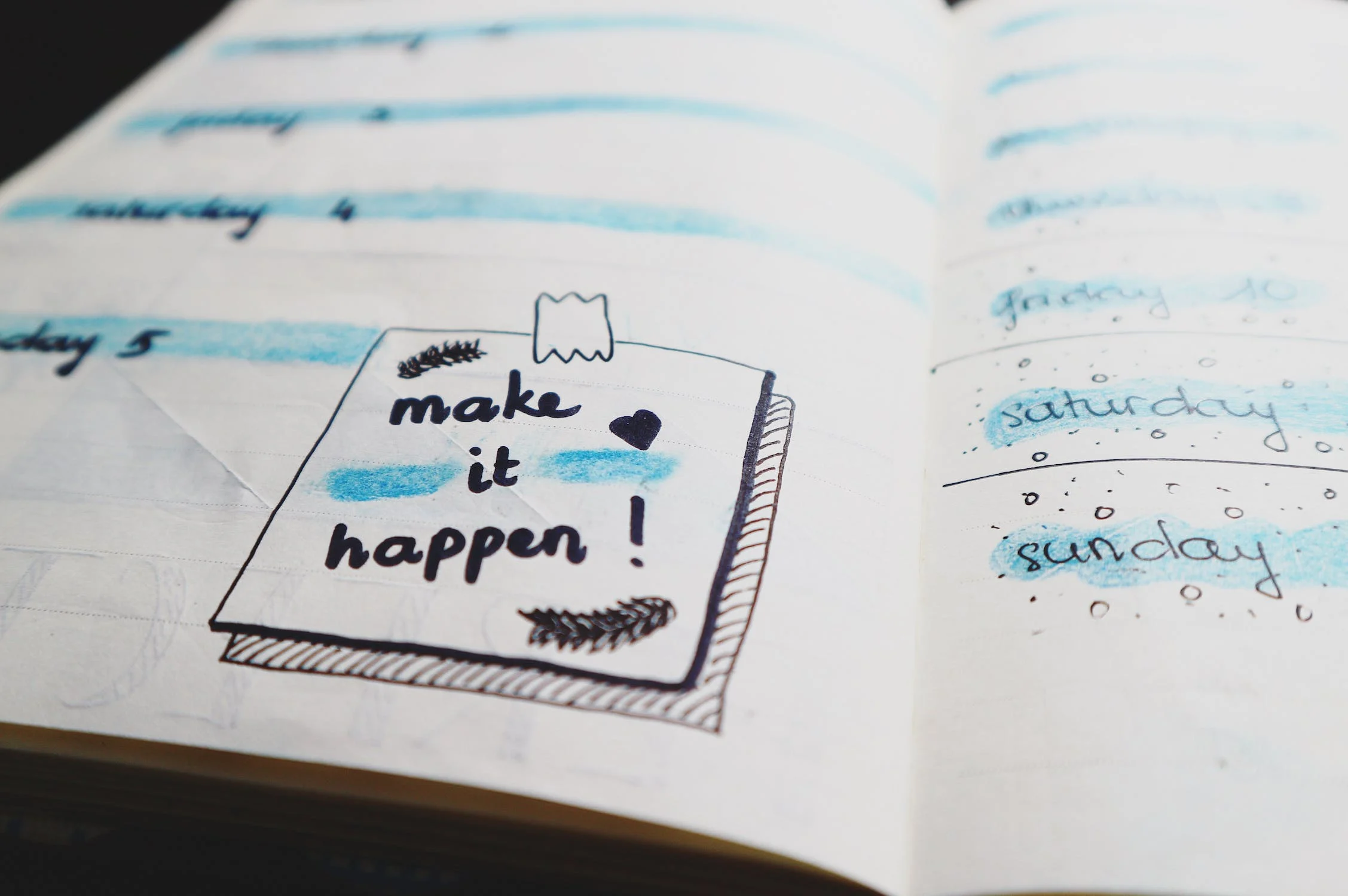 un cahier avec écrit "make it happen"