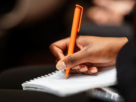 A woman writing something in her notepad with an orange pen