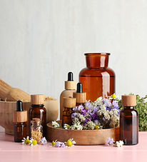 Aromatherapy. Different essential oils, mortar, pestle and flowers on pink wooden table.jp