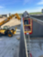Worker on lift managing cost of grain bin construction.