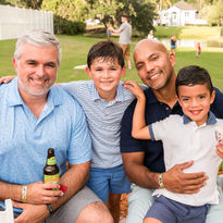 Two men and two young boys smiling at an outdoor event.