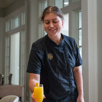 Chef in black uniform serving a fresh mimosa drink