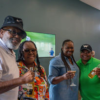 Four people smiling and holding drinks at a gallery event