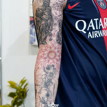 Detailed arm tattoo featuring art, text, and various figures Tribal Ink Tattoos new delhi.