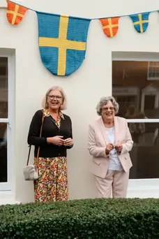 Two people stood in front of house and bunting