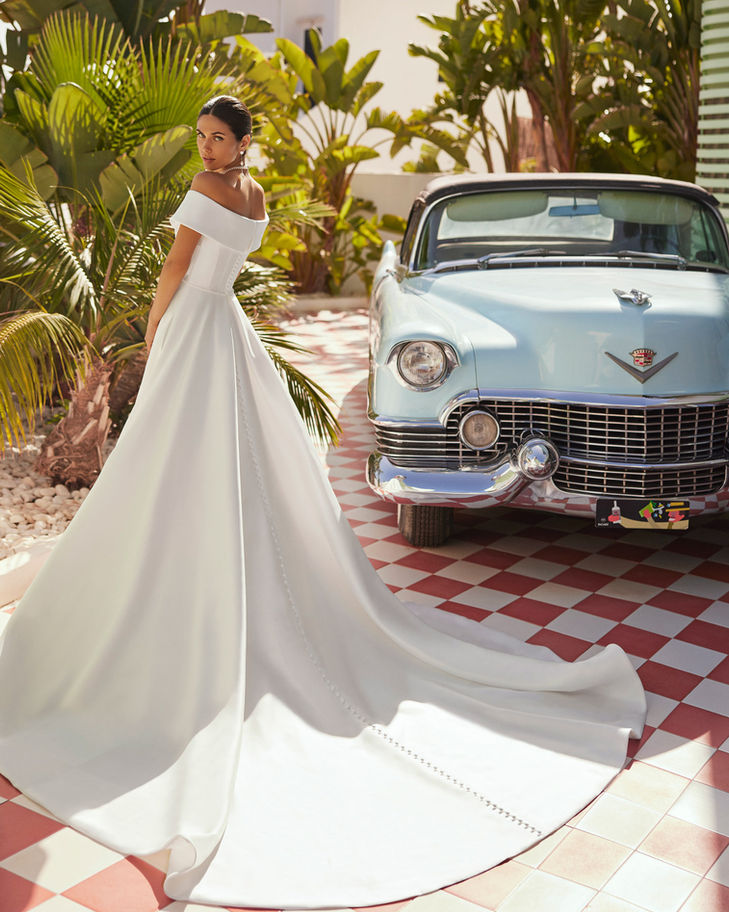 Elegant bride in off-shoulder gown, classic car backdrop