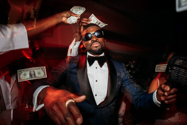 Man in tuxedo and sunglasses, money flying overhead