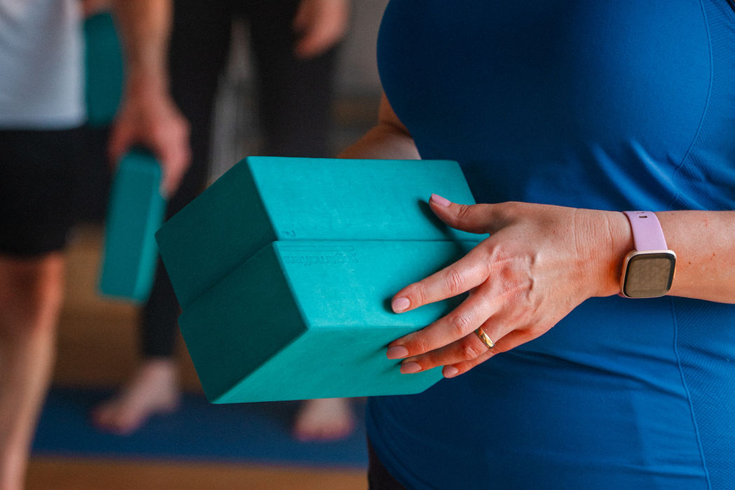 Female hands holding yoga foam bricks, a smart watch on one wrist