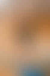 man doing a standing yoga pose, arms outstretched above him, stood on a blue yoga mat.