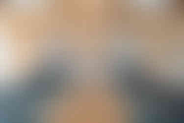 a man and a woman stood in a wooden yoga studio, doing a mirrored lunge yoga pose.