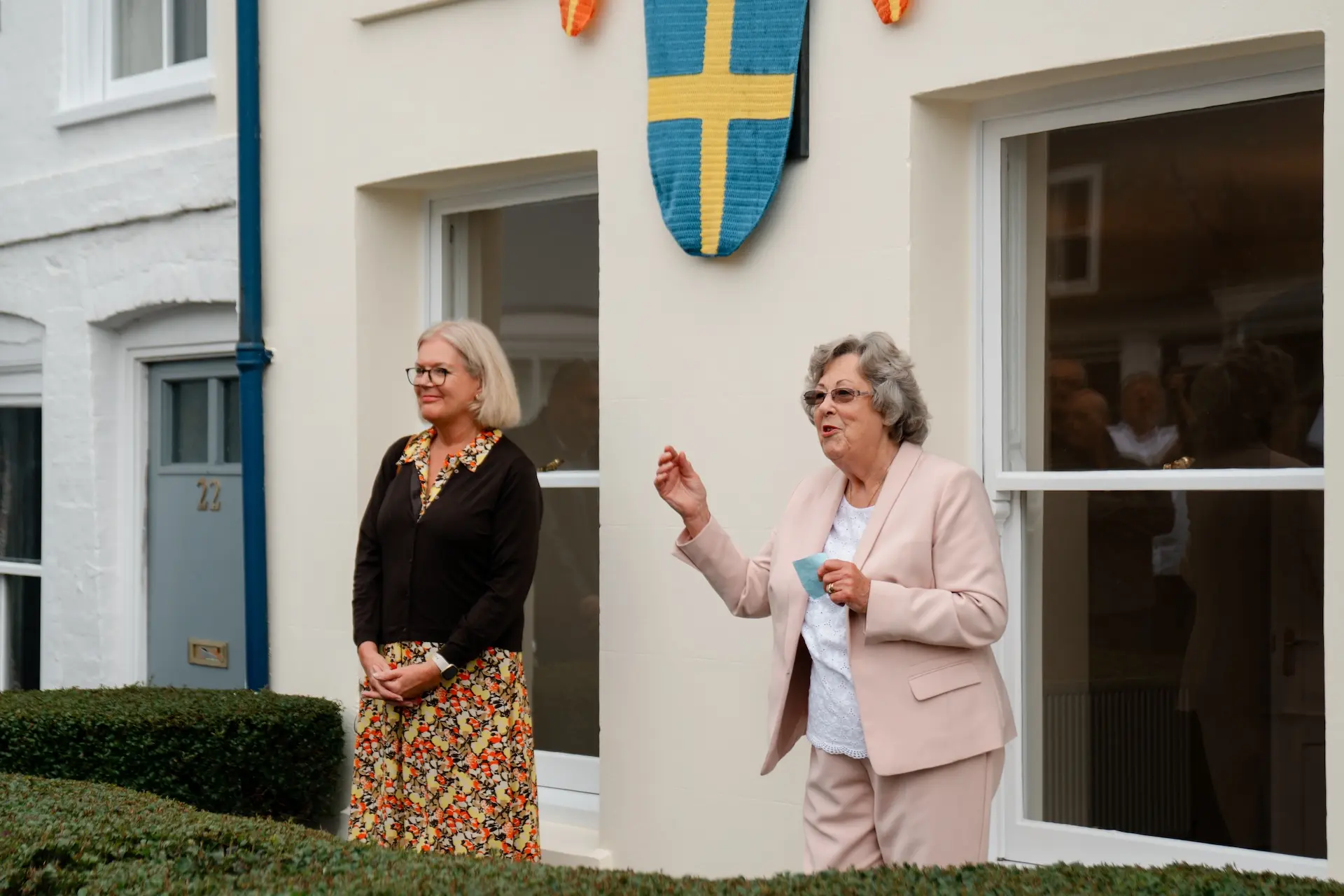 Two people stood in front of house with bunting