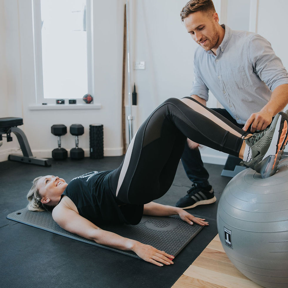 Woman doing stability ball bridge exercise with trainer
