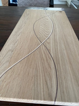 Eiken plank met lint erdoor, houten plank met gekleurde lijnen, op houten tafel.
