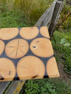 Houtwerkstuk van hergebruikt hout met boomschijven in hars op hek.