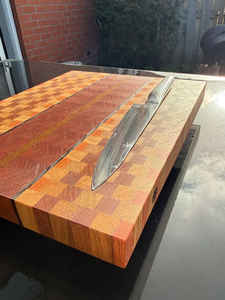 Houten snijplank met mes erop en chaotisch blokpatroon en donkere middenbaan.