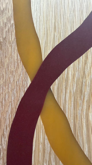 close up van roodbruine en gele epoxy linten op houtnerf.
