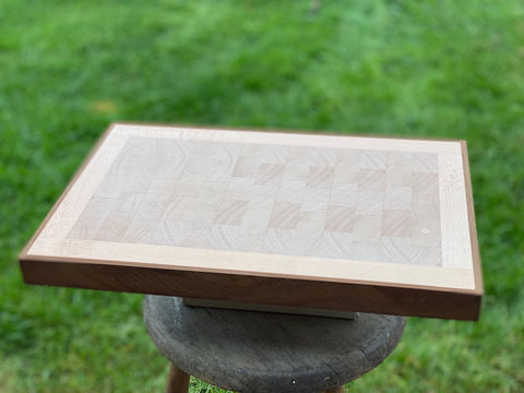 Houten snijplank, Snijplank 16 beuken met kebony kader, rustend op een groene achtergrond.