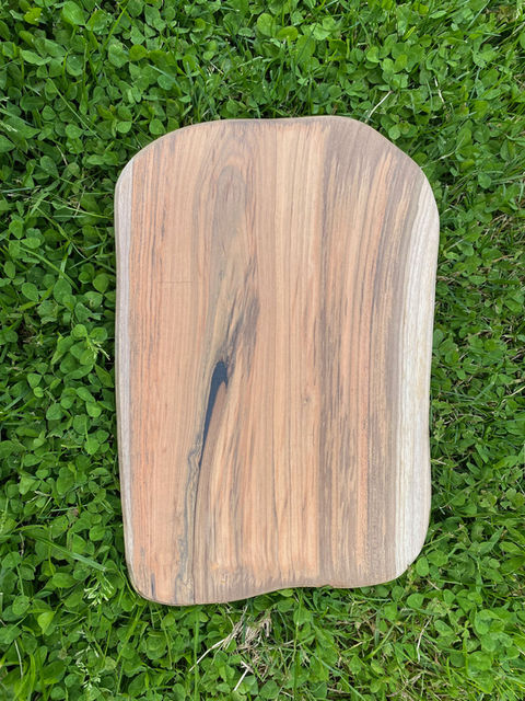 Houten snijplank op groen gras, eindresultaat van restauratie, Yuri's Houtwerk.