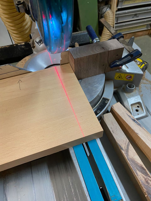 Houtbewerking met een verstekzaag, laserlijn op een plank, klaar om te zagen.