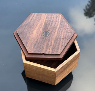 Houten hexagon doosje met logo, iets open.