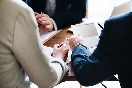 closeup of 3 businesspeople sitting around meeting table reviewing private investigator documents