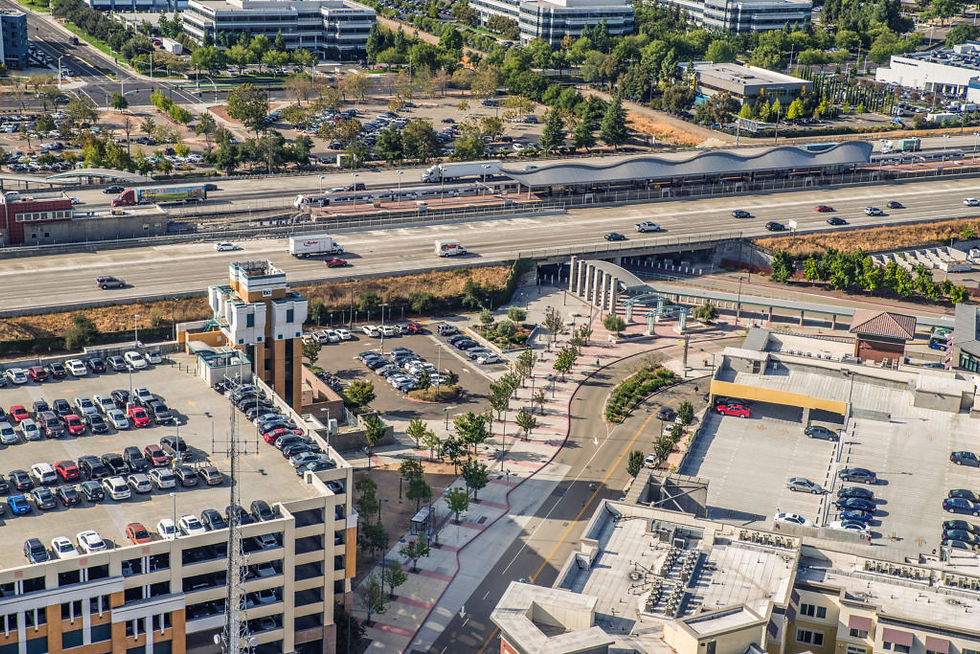Aerial view: urban transportation hub, highway, train station, parking lots.