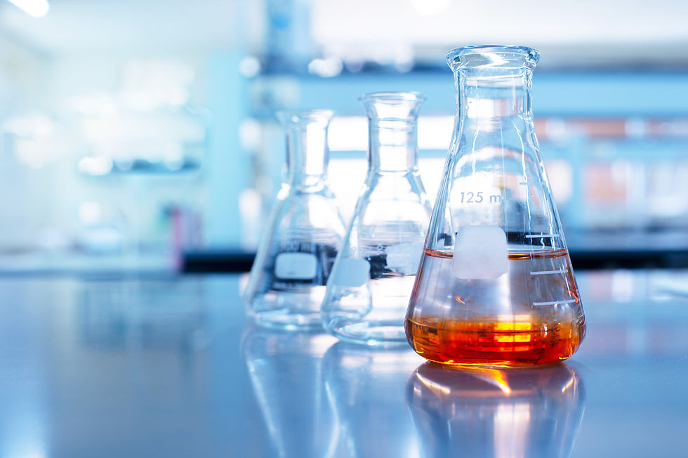 3 beakers on a lab table; one has orange liquid in it