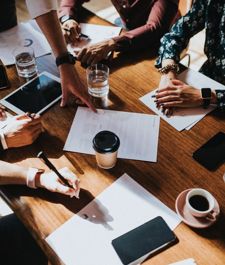 Top view of a team collaborating at a table with laptops, documents, and coffee cups