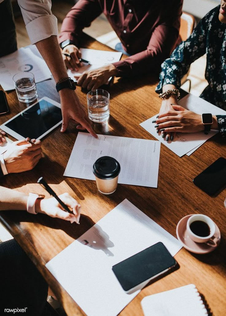 Top view of a creative team working together at a table with laptops, documents, and coffee cups