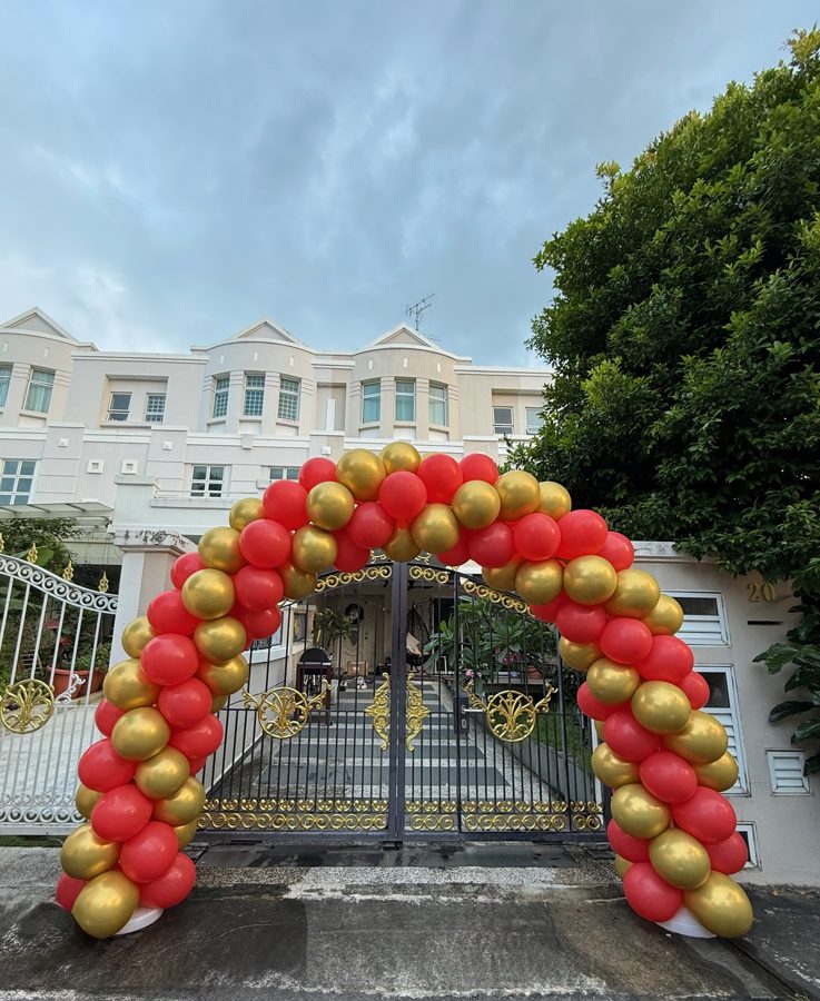 Red and gold balloon archway at a house gate